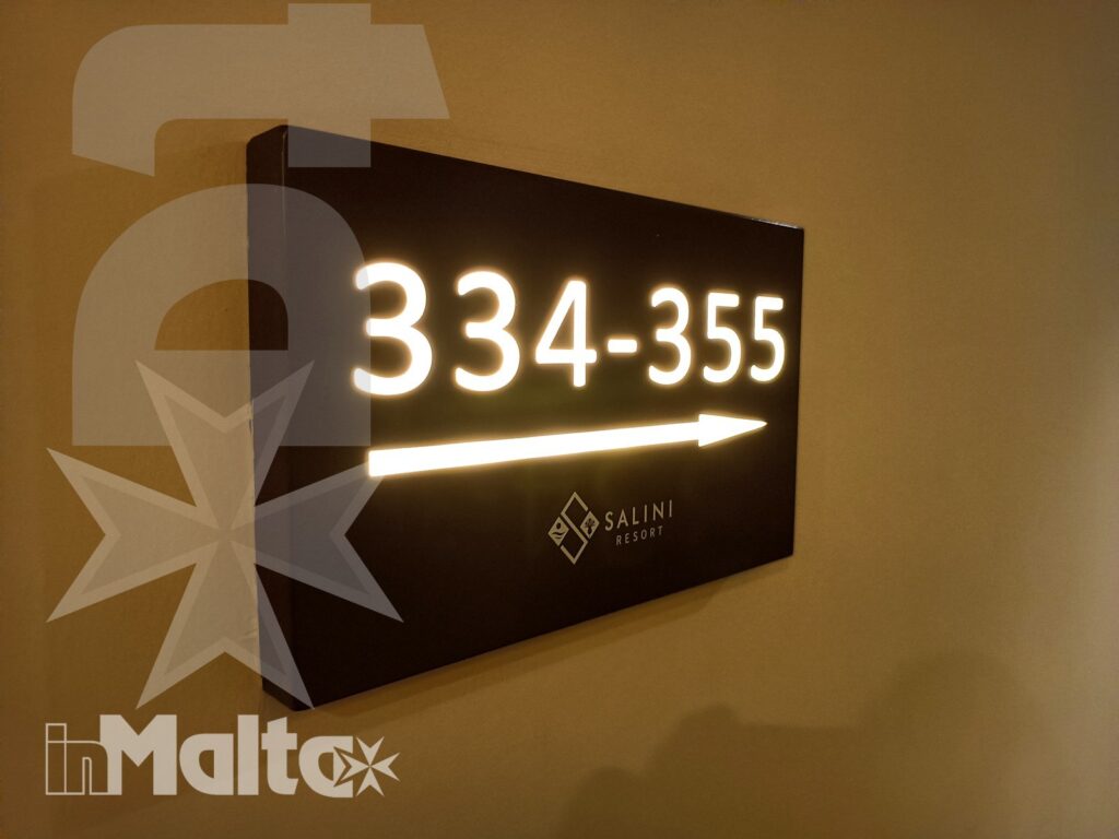 Cartello illuminato del Salini Resort con freccia direzionale e indicazione delle camere dal numero 334 al 355.