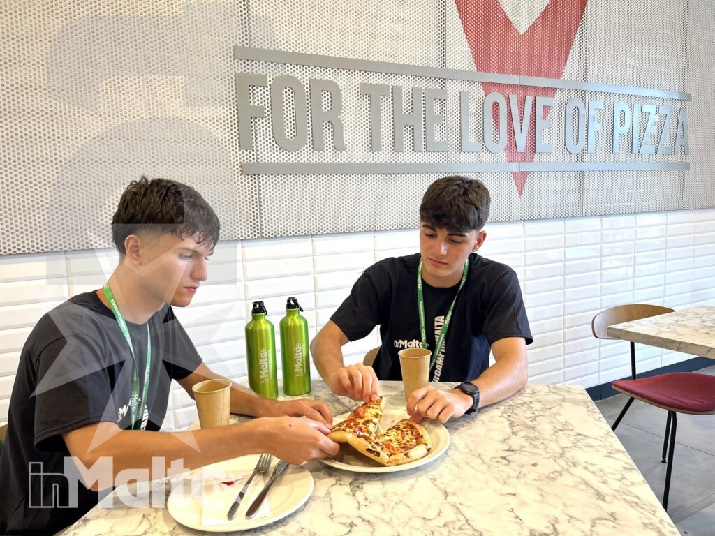 Due studenti condividono una pizza al tavolo di una pizzeria moderna durante il loro soggiorno studio.