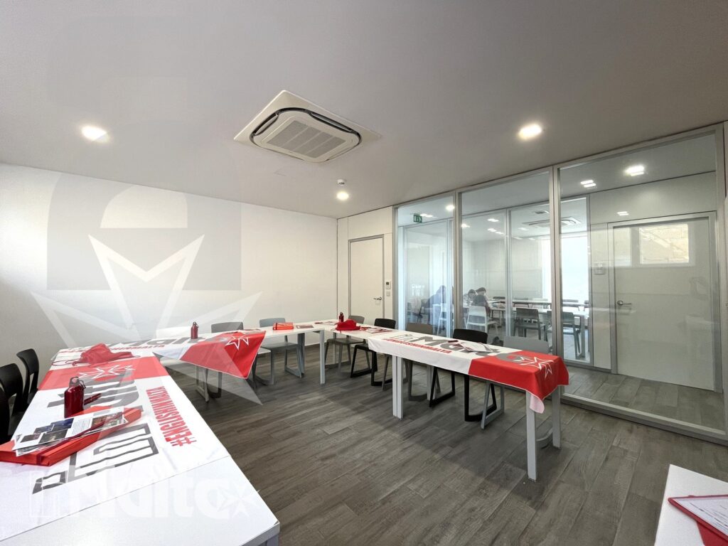 Aula moderna con tavoli disposti a U e materiali coordinati, predisposta per attività didattiche collettive durante una vacanza studio.