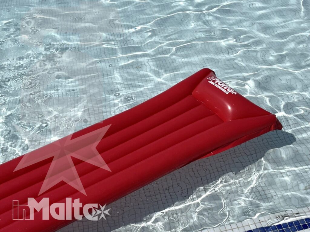 Materassino gonfiabile rosso che galleggia nell'acqua trasparente della piscina del Salini Resort a Malta.