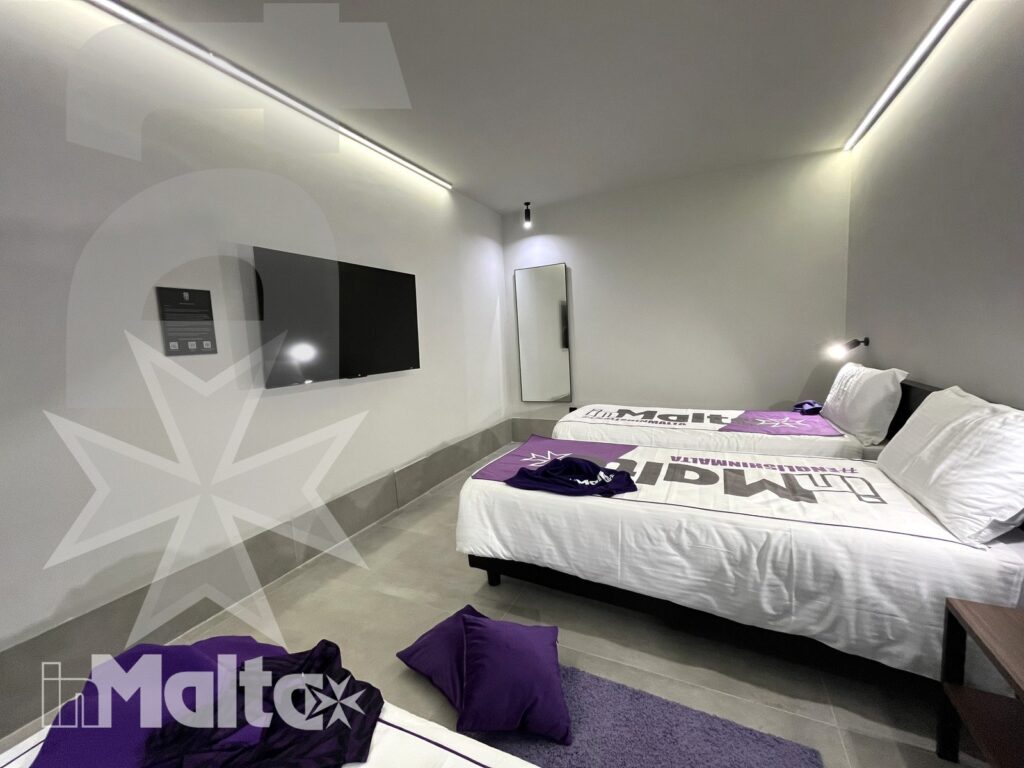 Camera moderna per partecipanti a Malta Camera moderna e ben illuminata con letto completo e dettagli strutturali, proposta di alloggio per partecipanti a Malta.
