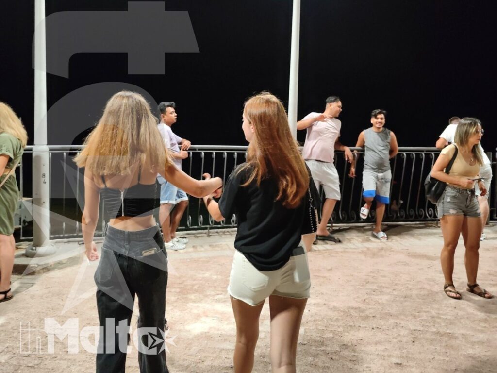 Studenti di diverse nazionalità ballano insieme su una terrazza all'aperto durante un'attività serale del soggiorno studio.